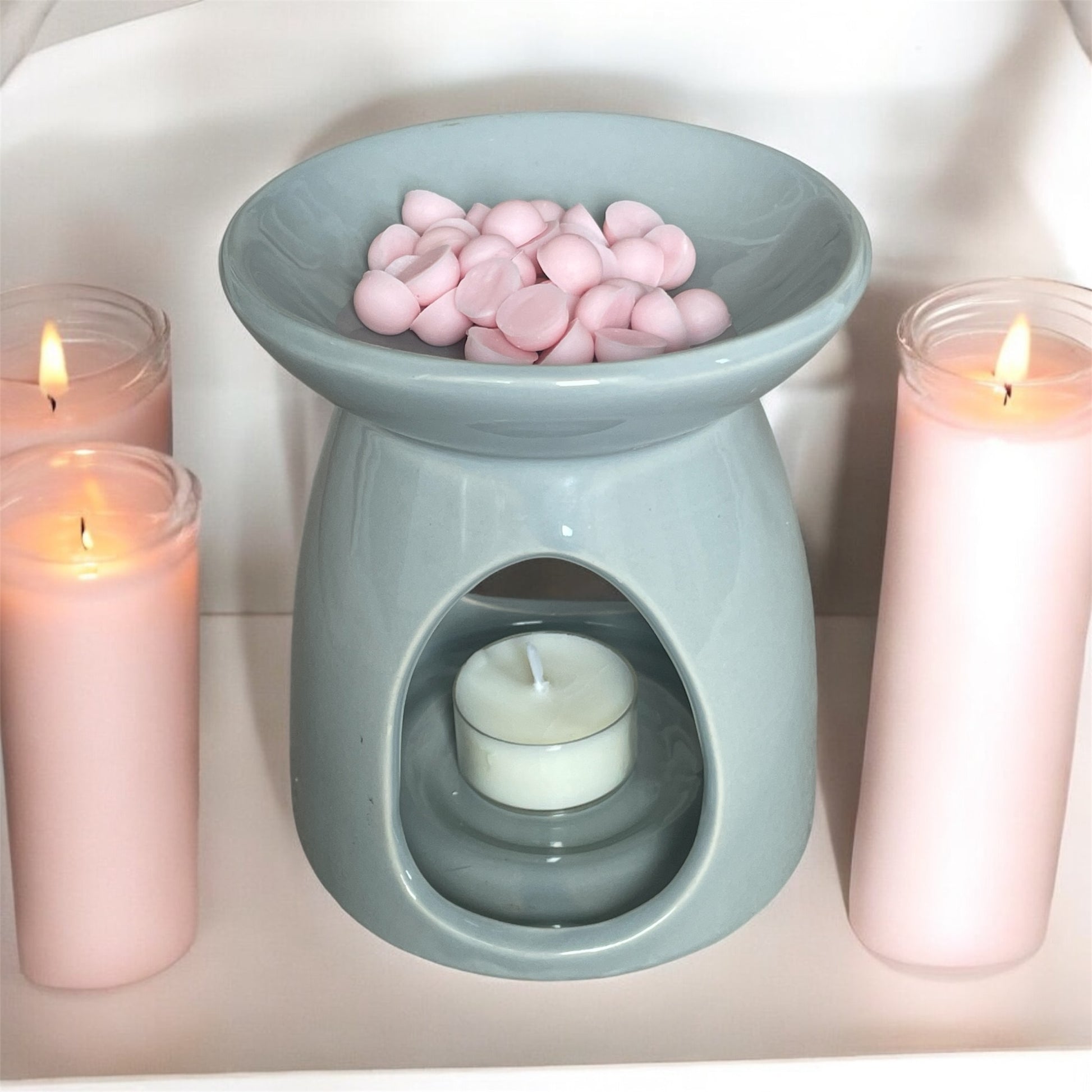 grey ceramic wax melt burner with tea light and pink candles, also with pink essential oils scoopie wax melts