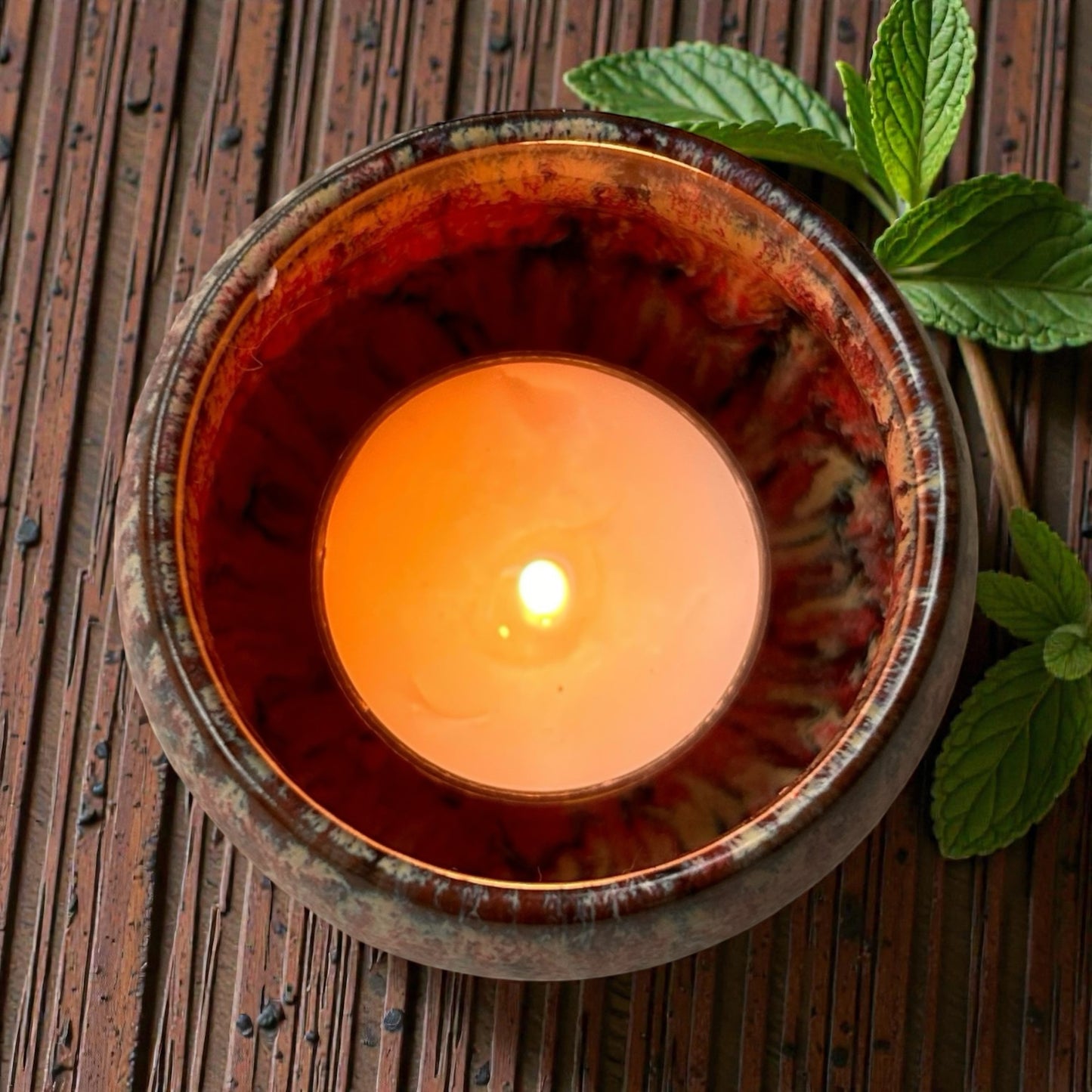 Clean Energy aromatherapy tea light burning in a ceramic holder releasing fresh essential oil fragrance