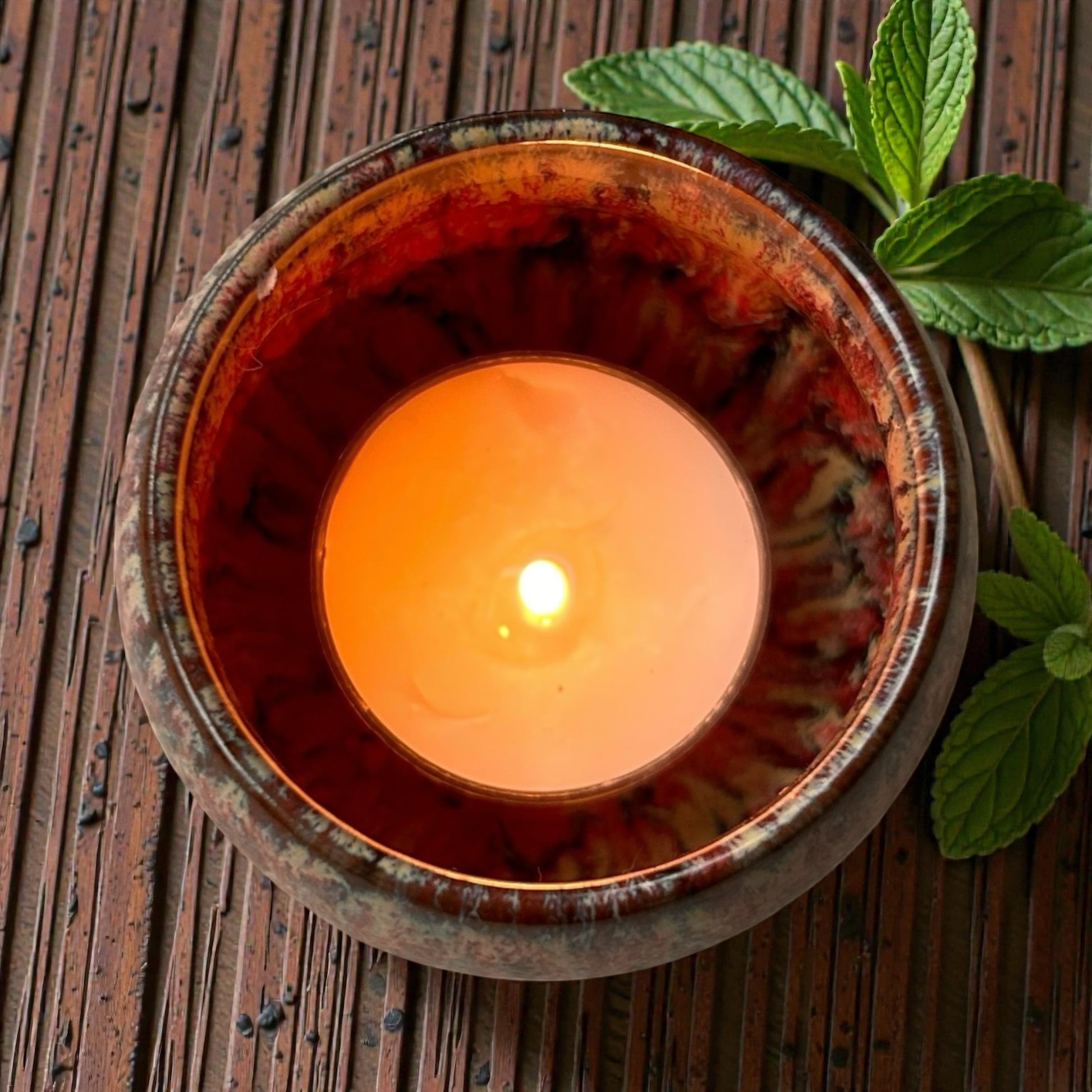 Clean Energy aromatherapy tea light burning in a ceramic holder releasing fresh essential oil fragrance