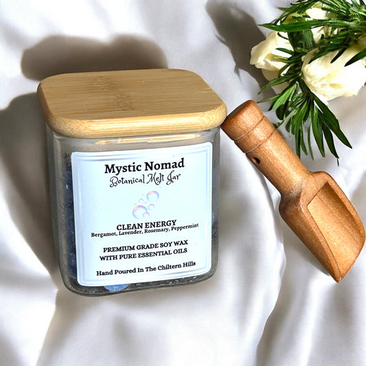 Lifestyle scene featuring Mystic Nomad Clean Energy aromatherapy wax melts in glass jar with bamboo lid, set on a wooden surface with fresh herbs and sunlight, creating a fresh, calming home environment
