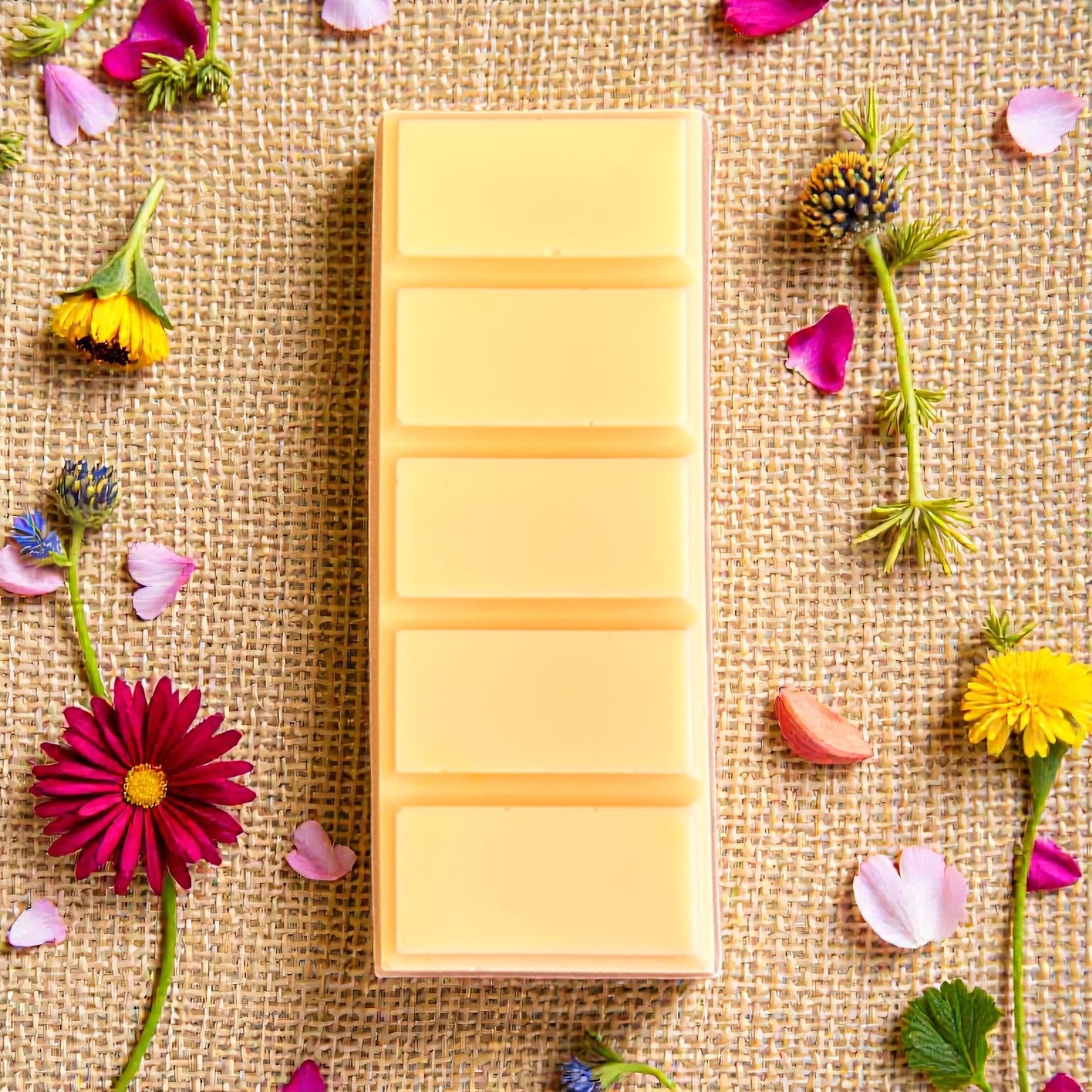 Wildflower Meadow aromatherapy wax melt snap bar by Mystic Nomad, surrounded by flowers. Hand-poured, eco-friendly wax melt for relaxation and mindfulness.